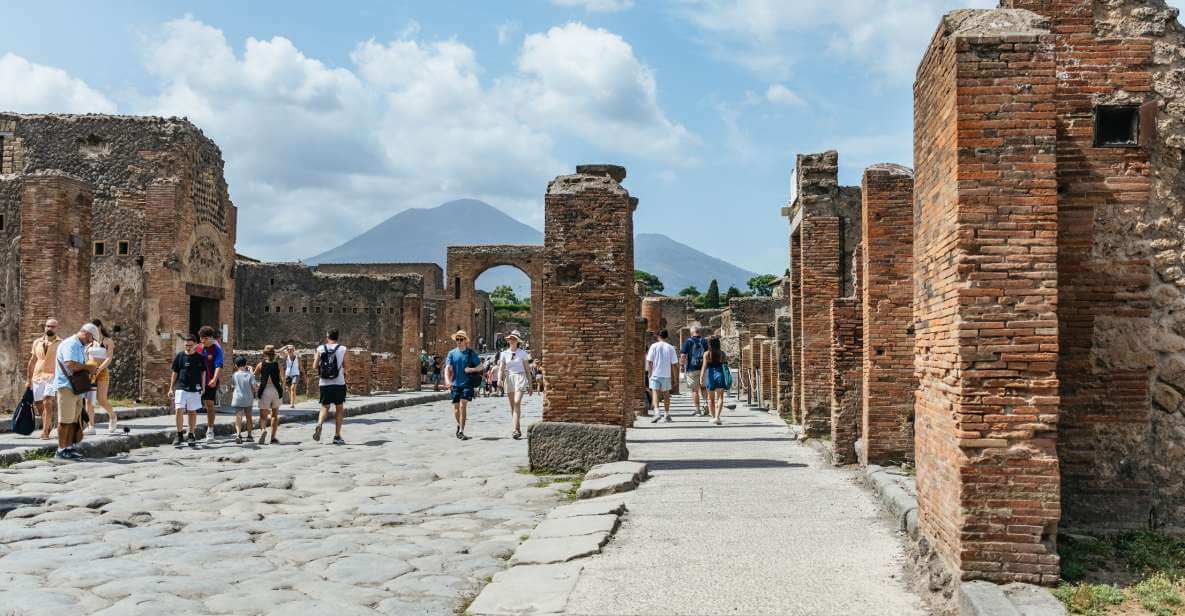 A group of tourists walking through pompeii, naples ruins on a sunny day in Italy.